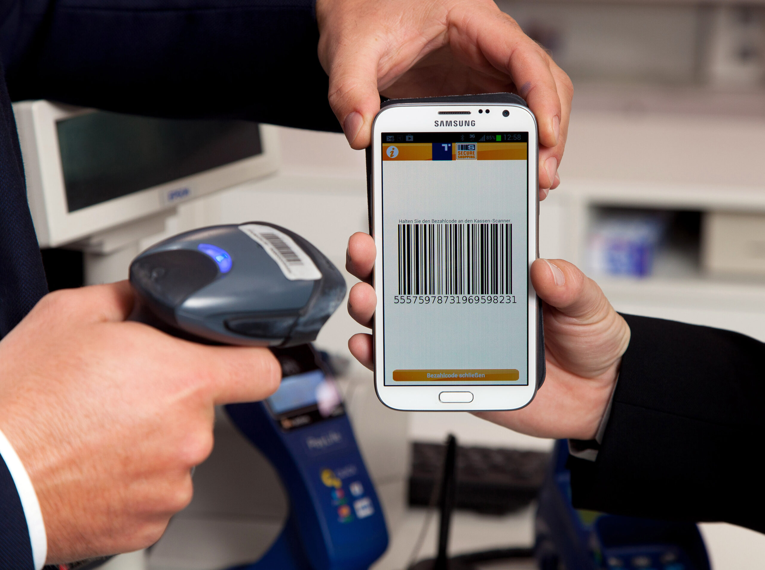 Smartphone displaying a payment barcode being scanned at a checkout.